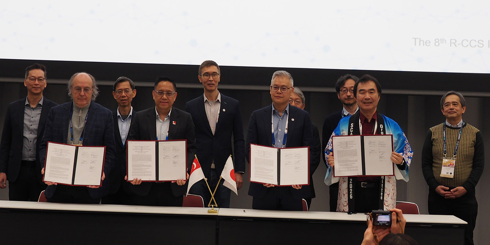 Ten signatories and witnesses of a Memorandum of Understanding stand in two rows at a table.
